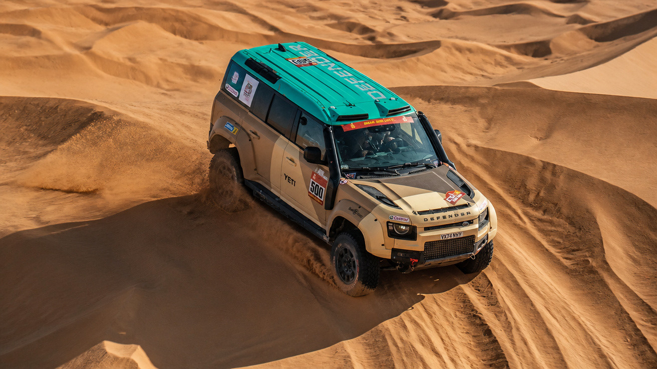Automóvel de rali 4x4 a conduzir em dunas de areia num deserto ao pôr do sol.